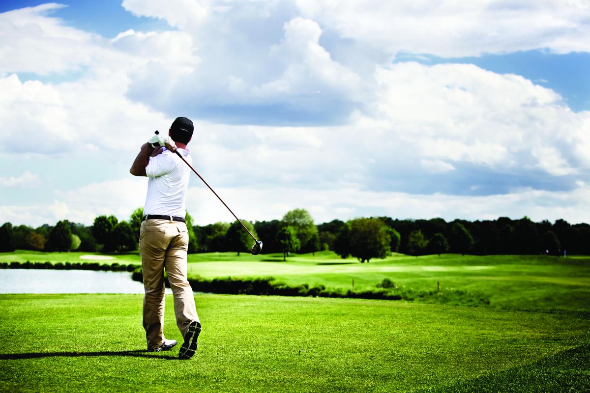 man golfing outdoors in mid-swing